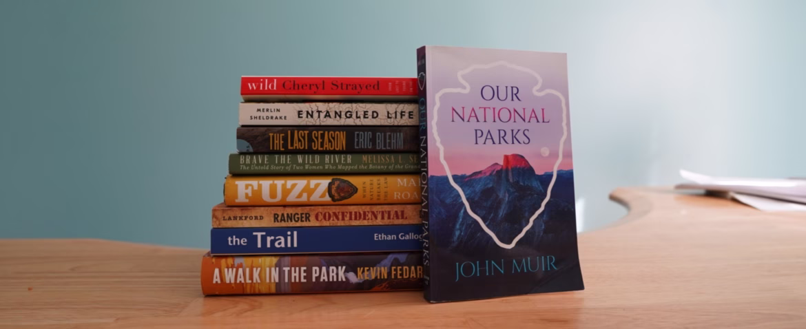 National Park Book Reviews and Reading Recommendations (2026) A stack of books, with spines facing out. They are Wild, by Cheryl Strayed. Entangled Life by Merlin Sheldrake. The Last Season by Eric Blehm. Fuzz When Natures Breaks the Law. Ranger Confiidential by Lankford. The Trail by Ethan Gallogy and A Walk in the Park by Kevin Fedarko. The cover of Our National Parks by John Muir features the NPS logo surrounding Half Dome.